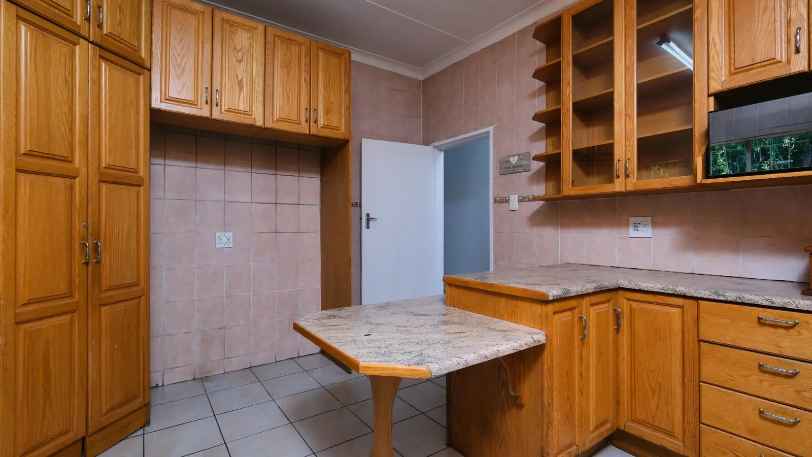 Kitchen before demolition showing outdated oak cabinets and dated finishes
